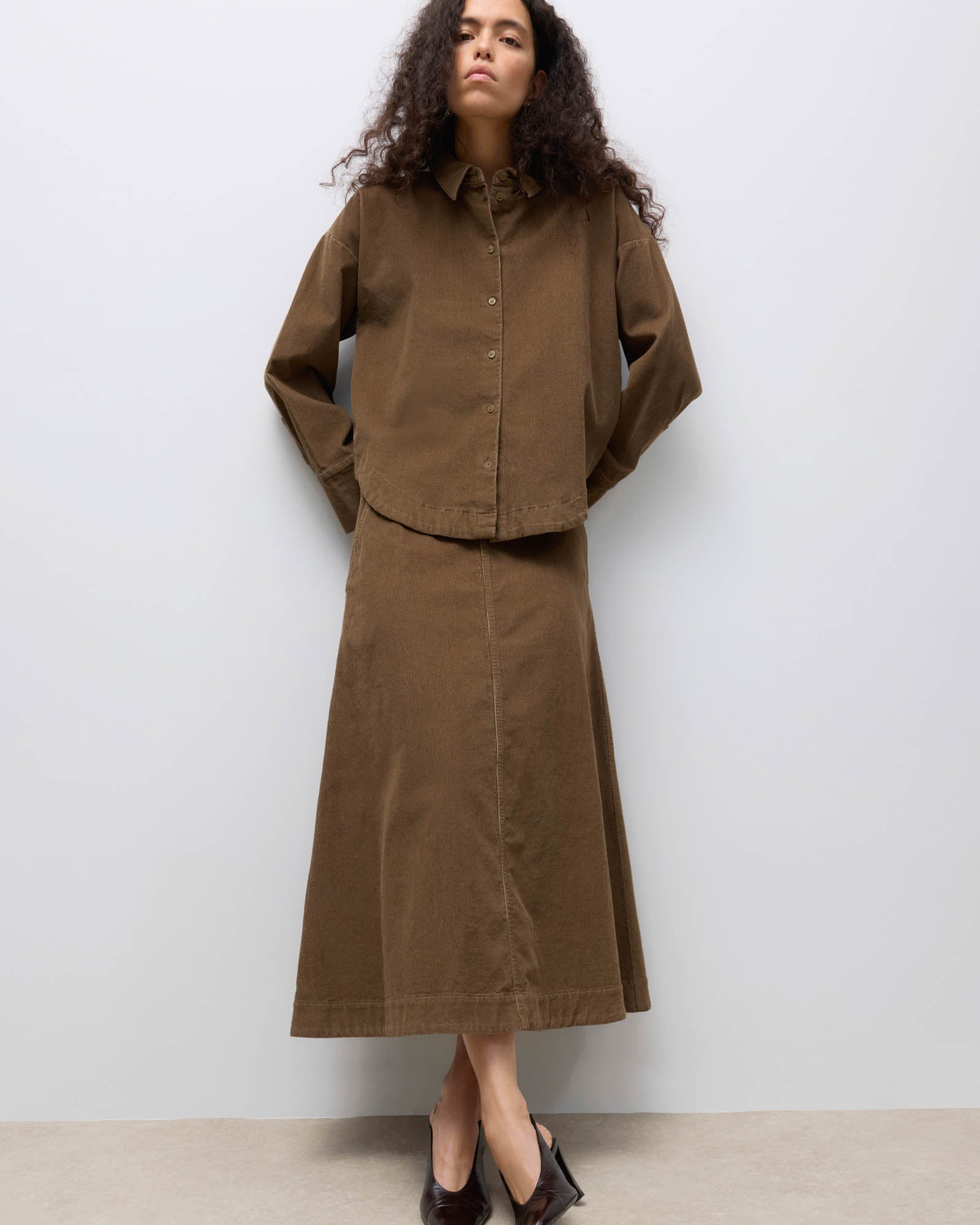 Woman wearing a brown outfit against a white background